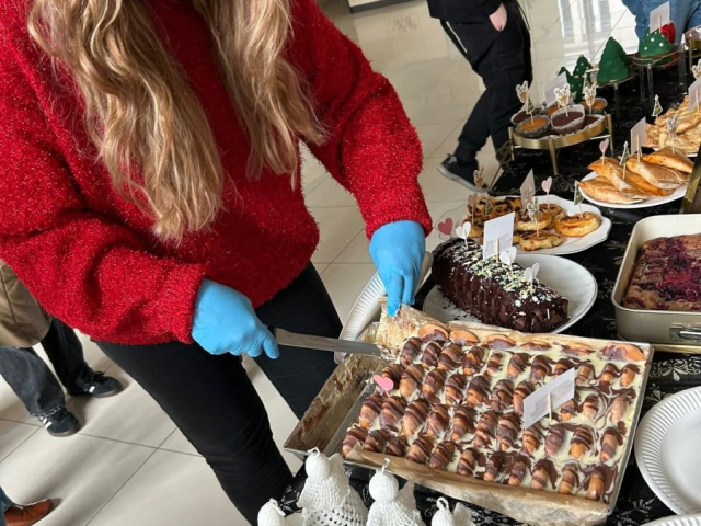 Członkini SKN „Elementarni”- Paulina Woźniak- krojąca ciasto podczas kiermaszu mikołajkowego