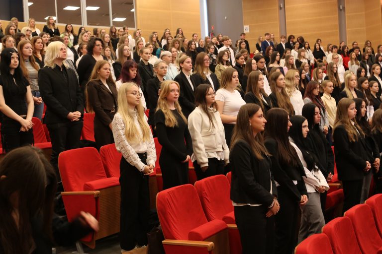 Studenci stojący w auli uroczystej inauguracji roku akademickiego 2026/2027